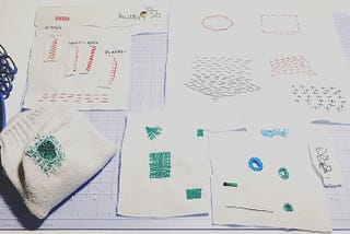 Four pieces of fabric and one sock with examples of mending techniques sewn into them.