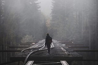 A person walking on broken railroad tracks. Why bother making choices and decisions to live your life?