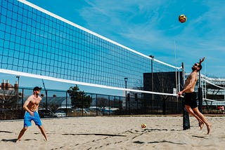 Students play beach volleyball on campus on a sunny afternoon