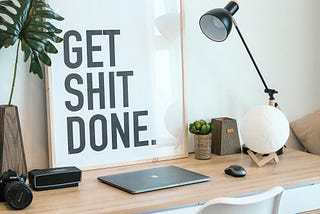 Working desk with laptop with a “Get shit done” poster