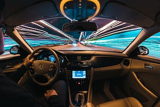 time lapse photo of a man driving a car taken from the interior, with visible lines of light outside the vehicle