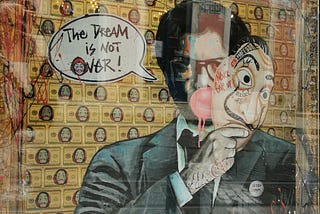 Rakel W painting currency in the background, anonymous mask with Dali mustache, guy blowing a bubble gum bubble, speech bubble saying, “The Dream is not OVER”)