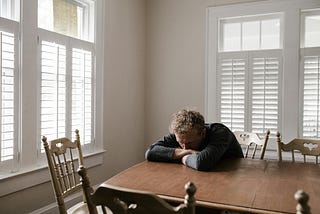 Person in Gray Long Sleeve Shirt Sitting on Brown Wooden Chair