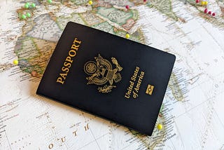 A US Passport book lying on top of a map of the world.