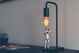 A small storm trooper toy looking up at a light bulb