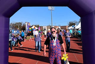 The author, John Carney, wearing donut-print Swoveralls, walking through an inflatable arch at the end of the Rutherford County Walk To End Alzheimer’s on Nov. 2, 2024.