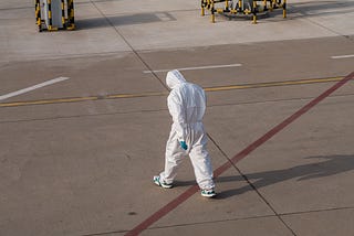 A tired looking person in a full-body protective suit, symbolizing the intersection of public health and safety.