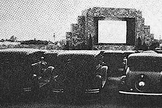 Several cars facing a large outdoor movie screen