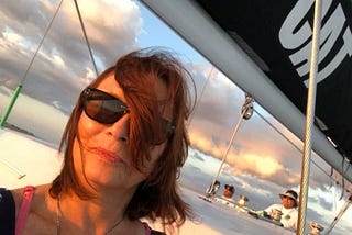 Red haired woman on a Catamaran, sunglasses, truthful face