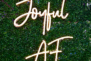 A light sculpture with the words “Joyful AF”