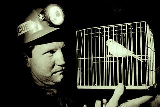 A coal miner holding a cage with a canary inside