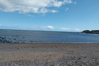 Shingle beach with calm blue sea and pale blue sky in April