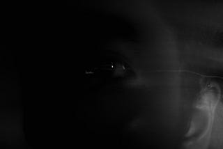Black eyed person looking at camera in darkness