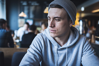 Man in a beanie at a coffee shop — This Boring Article Type Makes Me $100 Per Day