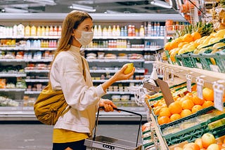 Woman wearing a surgical mask and holding fruit in a supermarket