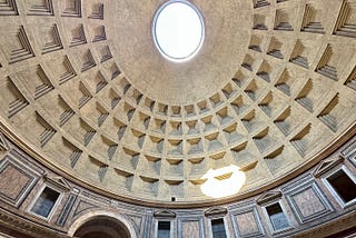 The roof of the Pantheon in Rome with sunlight casting a bright spot on the side wall.