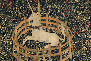 Medieval tapestry of a unicorn kneeling inside a very small fence, surrounded by elaborate flowers and plants.