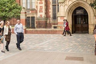 people walking in front of the great hall on campus