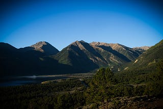 Green hill slopes and mountains in the background under a blue sky.