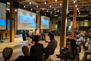 4 panelists, a moderator, and an ASL interpreter sit in front of an audience during Disability Connect at Adobe SF.