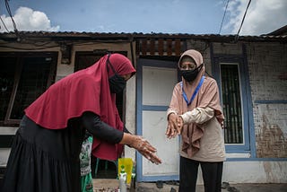 Sri Rostiaty was mentoring Farida on a handwashing exercise in front of her house while Farida’s son was observing the exercise up close. Photo by Andri Ginting