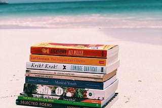 A stack of Caribbean books on a beach in Antigua.
