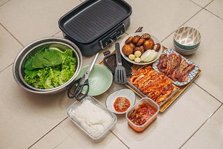 kimchi, rice, Korean BBQ on a tiled ground insinuating being able to cook pungent food when living alone