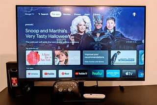 Picture of a smart computer monitor with Google TV landing home page displayed. In the bottom row of apps, the Google Stadia app is visible and installed.