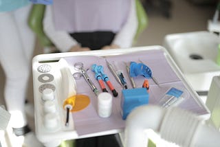 dental equipment on a tray in front of a patient sitting in the exam chair