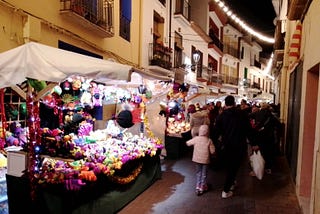 A narrow village street full of craft stalls and people