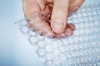 Hand popping a piece of bubble wrap.