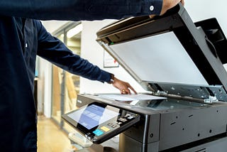 A person puts a document on top of a flatbed scanner getting ready to scan the document.