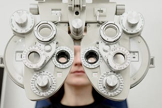 A subject behind a “phoropter” used to determine the refractive power of each eye and the possible need for glasses
