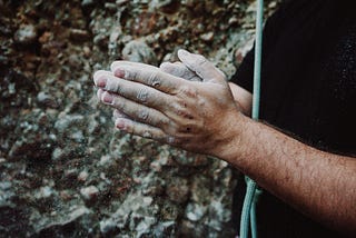 Rock climber’s hands cover with chalk.
