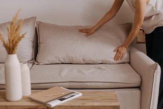 A person setting the living room sofa cushions to organize home.