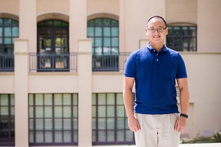 A person (Henry Ngo) wearing a navy polo and khaki slacks; in the background is the Sherman Fairchild Library at the California Institute of Technology