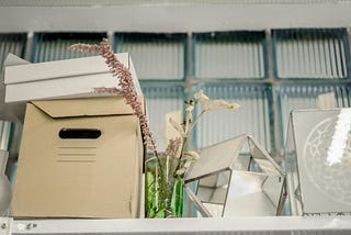 A box on a white shelf. In the center is a small dried flower arrangement