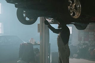 A mechanic carrying out a repair on a car in a dusty garage