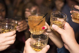 Five people holding their drinks up as a toast.