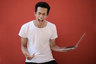 Young ethnic male with laptop screaming