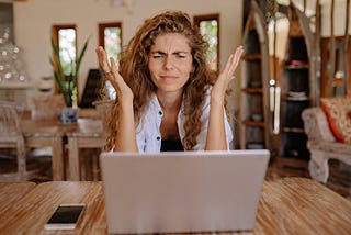 A frustrated woman sits at a desk in front of a computer