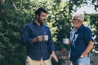 old father and son having morning coffee in a garden