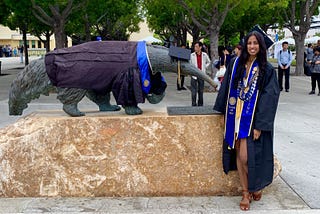 A picture of me, Ami, in my graduation attire in front of an Anteater statue.