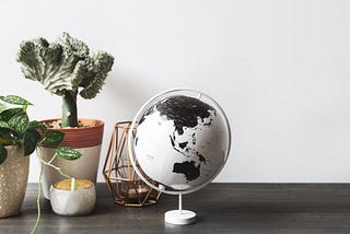 A black-and-white globe on a table with plants and candles.
