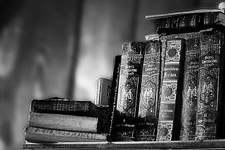 A greyscale picture of a few old books on a shelf — signifying wisdom.