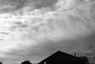 a roof and a cloudy sky in black and white