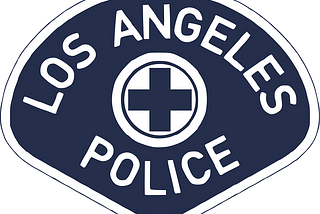 An illustrated image of the Los Angeles Police Department badge, white writing on a deep blue background. In the center of the badge is a blue plus sign outlined in a white circle.