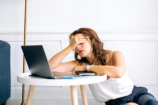 Woman in White Spaghetti Strap Top and Blue Shorts Sitting on Floor Feeling Exhausted