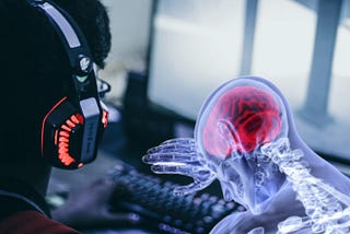 A person with a gaming headset, faceless, in front of two computer monitors that are blurred in the background. A nervous system skeleton PNG can be seen in the right corner, hunched over the keyboard.