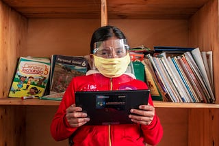 This learner wearing a mask and face shield in Peru is using Kolibri to continue her studies amid the pandemic.